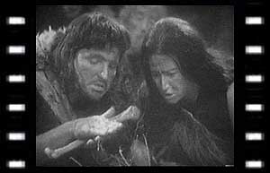 Image of Za (Derek Newark) making fire while Hur (Alethea Charlton) watches