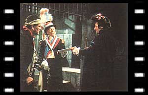 Image of The Doctor presenting papers to Lemaitre (James Caincross) with the Jailer (Jack Cunningham) watching