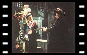 Image of The Doctor presenting papers to Lemaitre (James Caincross) with the Jailer (Jack Cunningham) watching