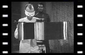 Image of Scientist (Vernon Dobtcheff) preparing the conditiioner while the War Chief (Edward Brayshaw) looks on